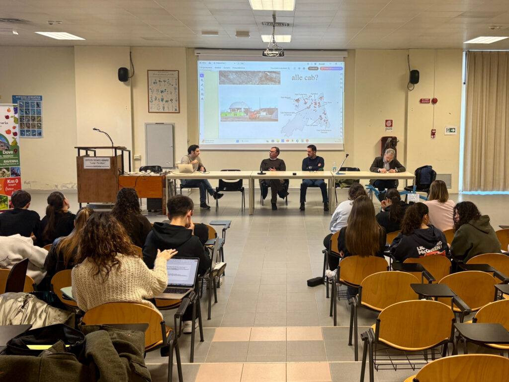 Incontro del progetto Semi di Cooperazione: relatori al tavolo davanti agli studenti nell'aula magna dell'istituto agrario